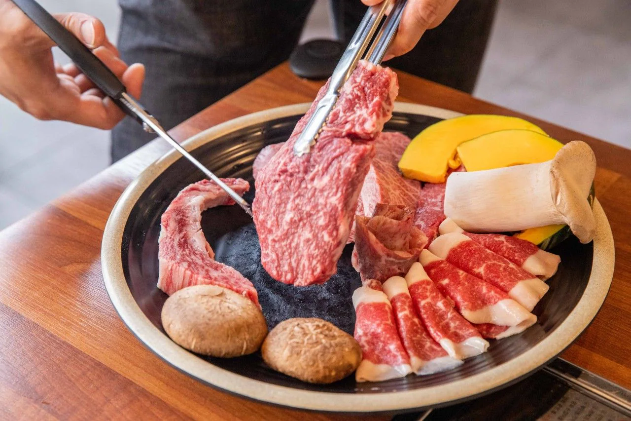 在烤盤上用夾子與剪刀剪肉的手