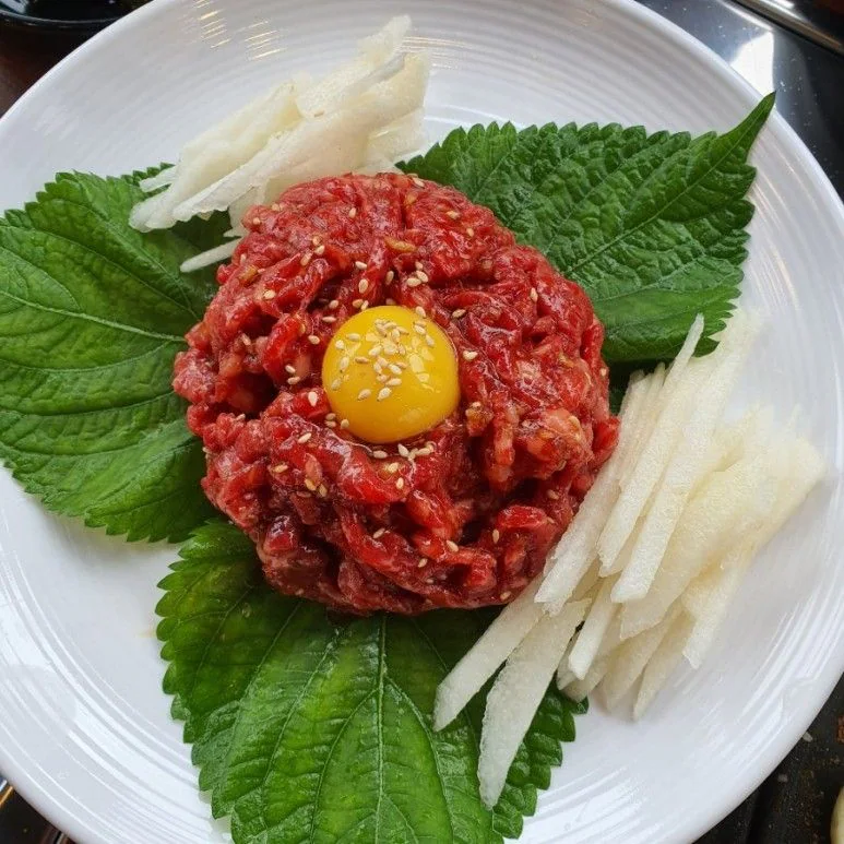 紫蘇葉上的生拌牛肉與蛋黃,旁邊是梨絲